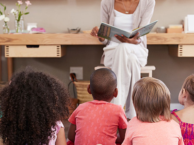 Photo of adult reading to a group of captivated children.