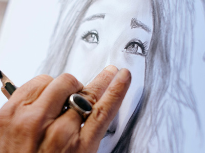 Mature hand seen drawing a portrait of a woman tourist.