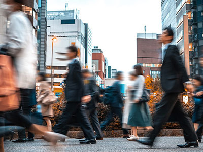 Photo of urban crosswalk with blurs of people crossing the street.