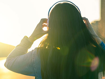 Silhouette of a person walking outside with headphones on.